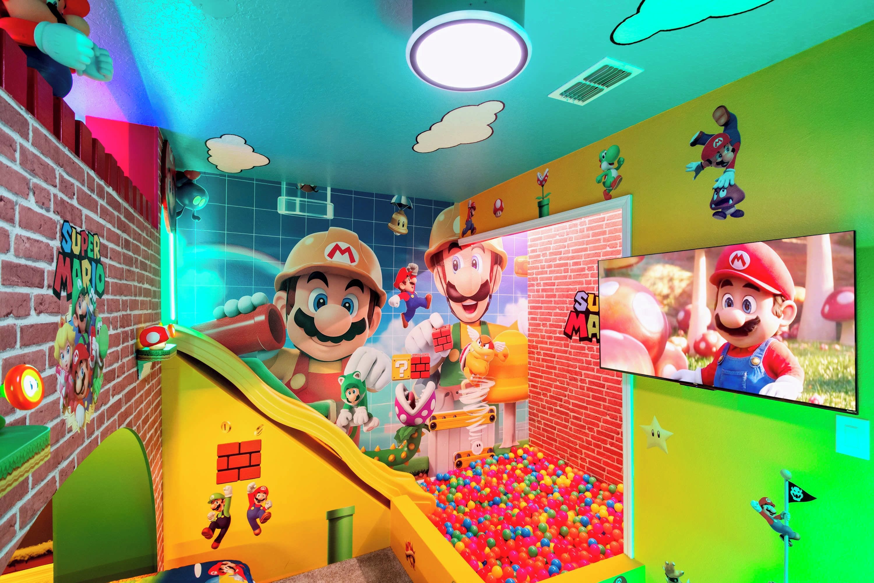 Een kleurrijke speelruimte met een glijbaan, bällebad en Mario-decoraties.