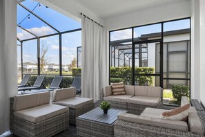 A sunlit patio with wicker furniture, a table, and a view of the neighborhood. - Lakeview Home w/ Mario Game Room & Themed Bedrooms (Kissimmee)