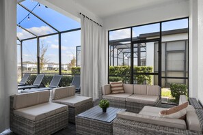 Un espace extérieur ensoleillé, aménagé avec des meubles en osier et offrant une vue sur le quartier.