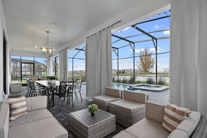 A spacious patio area with outdoor furniture, a dining table, and a view of a swimming pool. - Lakeview Home w/ Mario Game Room & Themed Bedrooms (Kissimmee)
