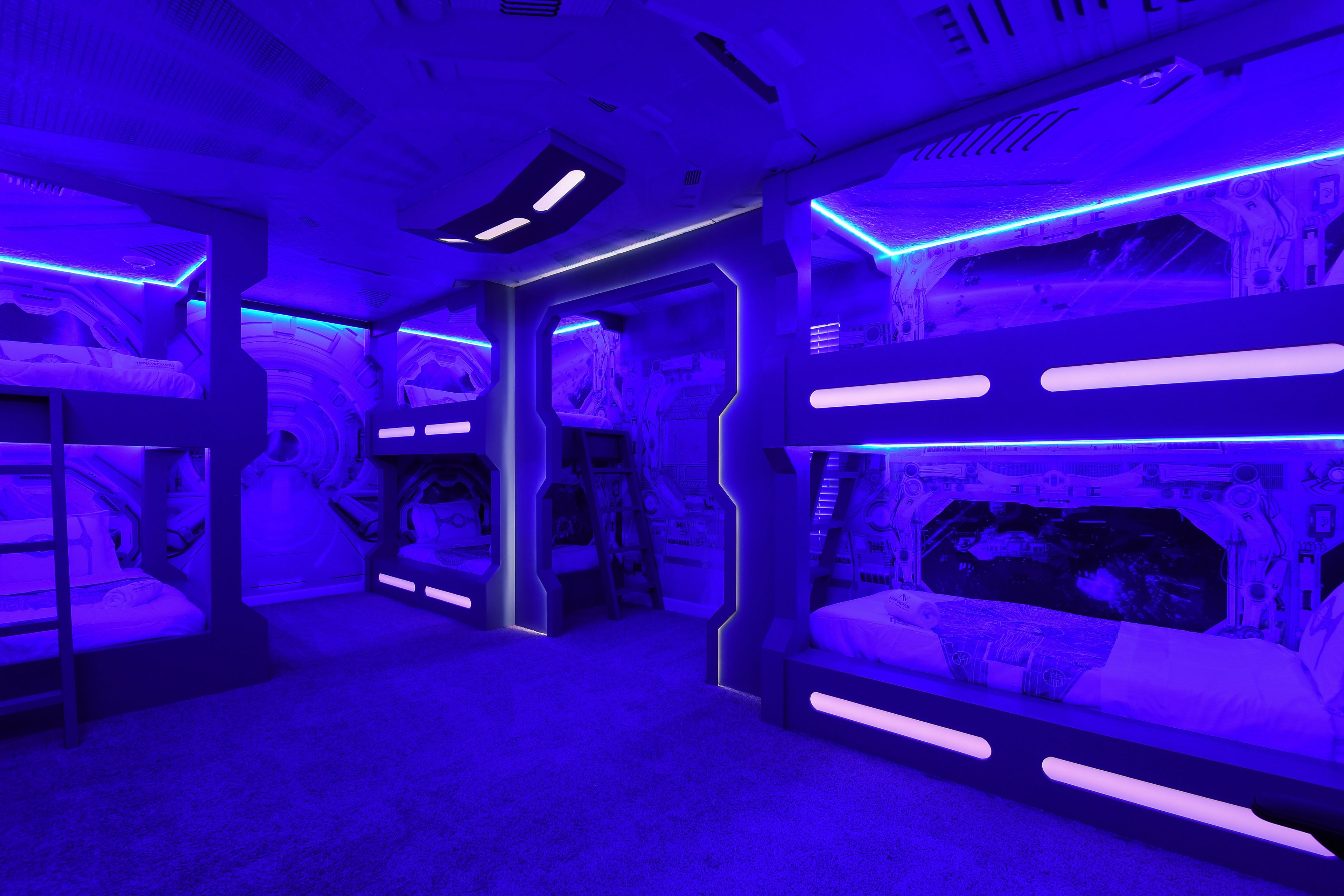 A room with bunk beds, a ladder, and a control panel.