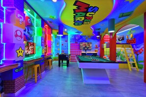 A brightly lit indoor space with a pool table, stools, and various colorful wall decorations. - Lakeview Home w/ Mario Game Room & Themed Bedrooms (Kissimmee)
