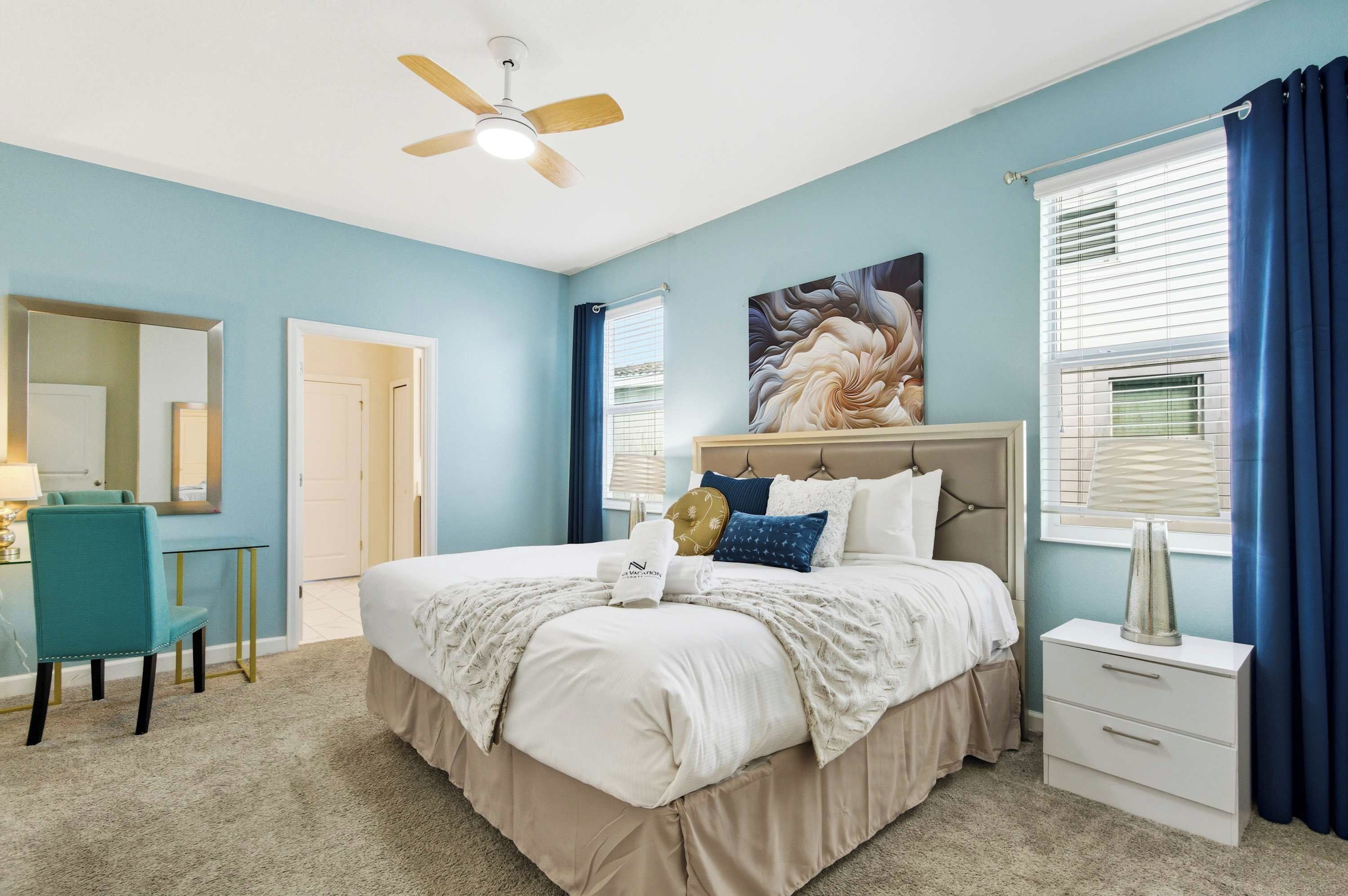 A bedroom with a bed, bedside table, chair, and a ceiling fan.