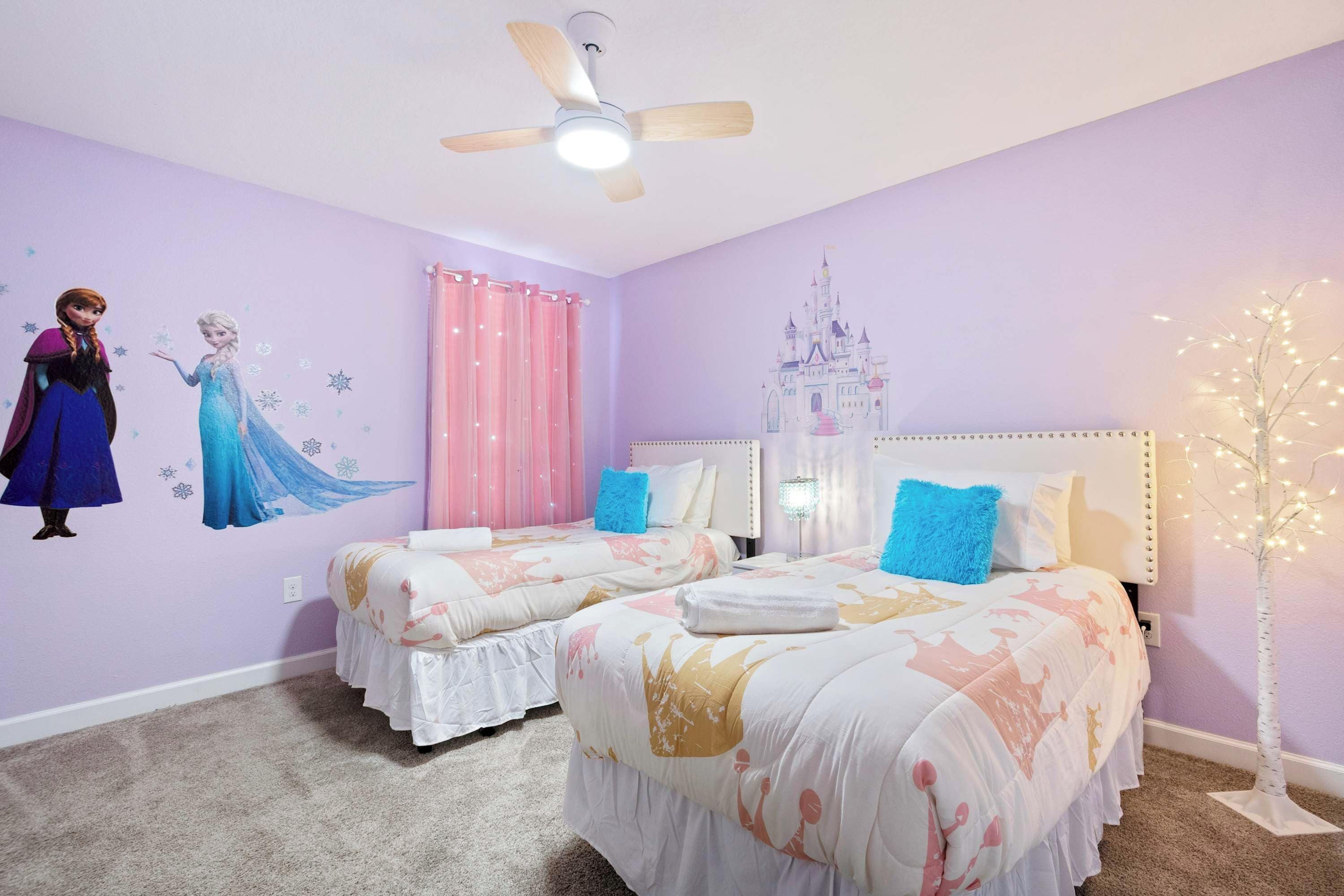 A bedroom with two beds, a ceiling fan, a castle mural, and a tree decoration.