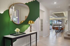 A modern interior with a console table, a mirror, a lamp, and a vase with flowers. - Family Fun Villa: Themed Rooms, Private Pool & Spa (Clermont)