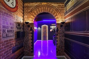 A brick-walled hallway with a wooden door labeled "Potions 8-3" and a sign reading "Have you seen this wizard?" - Family Fun Villa: Themed Rooms, Private Pool & Spa (Clermont)