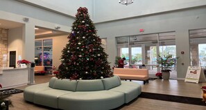Un hall con un gran árbol de Navidad, una recepción y una zona de estar.
