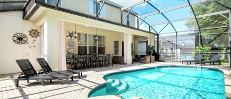 A covered outdoor swimming pool with lounge chairs and a dining area.