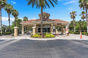 A hotel entrance with a gated driveway, palm trees, and a clear blue sky. - Mario, Mickey & Jedi Arcade Villa w/ Themed Rooms (Kissimmee)