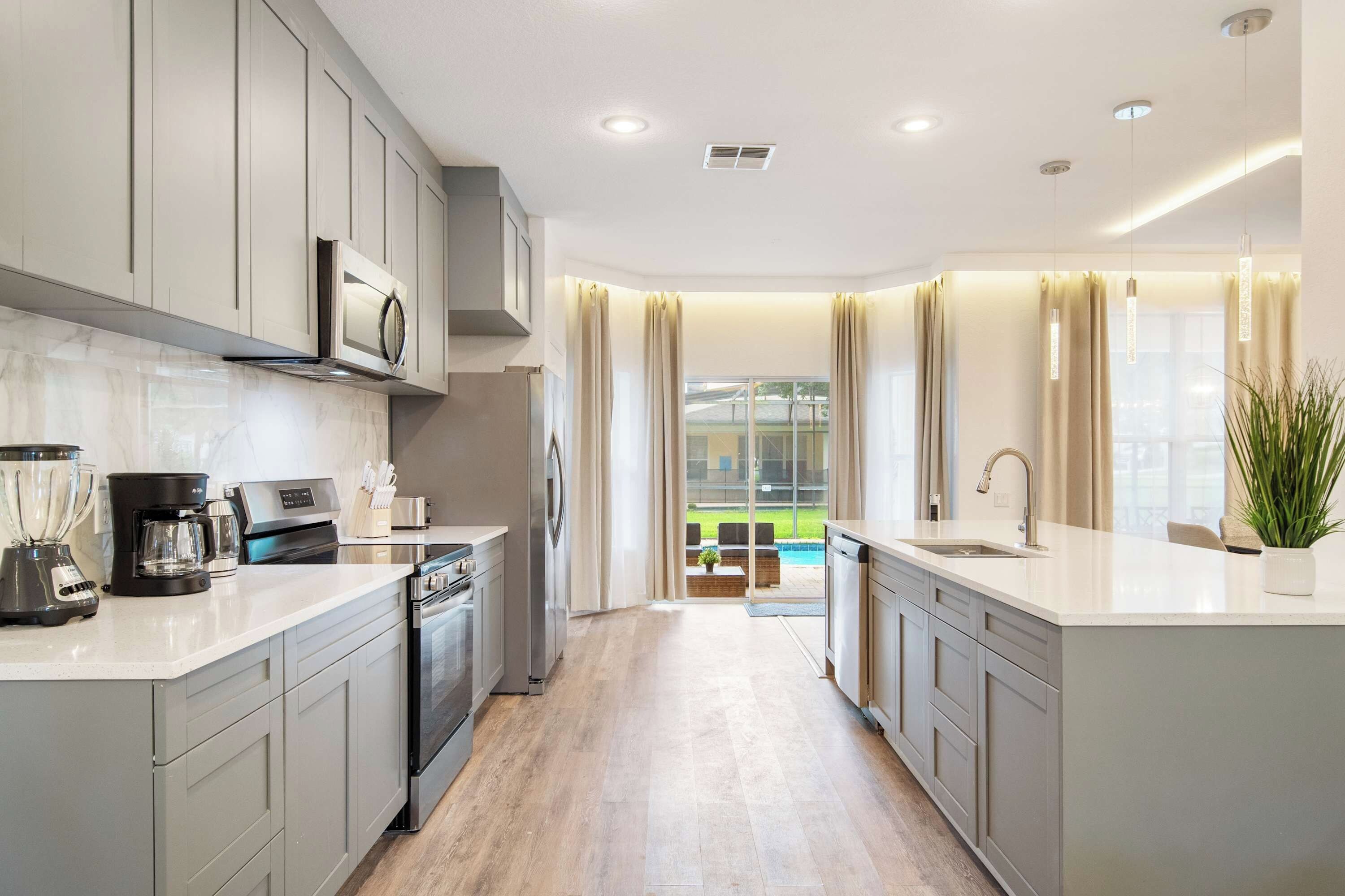 A modern kitchen with grey cabinets, a built-in oven, and a coffee maker.