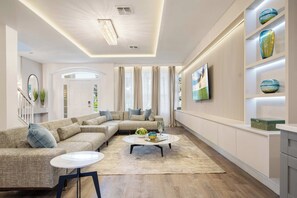 A modern living room with a sectional sofa, a round coffee table, and a bookshelf with decorative items. - Mario, Mickey & Jedi Arcade Villa w/ Themed Rooms (Kissimmee)
