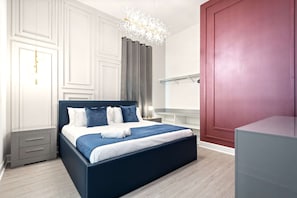 Ein modernes Schlafzimmer mit einem großen Bett, Nachttischen, einem Spiegel und einer roten Tür.