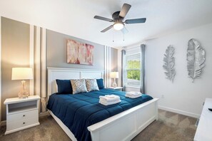 A bedroom with a bed, nightstands, a ceiling fan, and decorative wall art. - Games/themed Rooms/greenview/ 9BR @ Storeylake! (Kissimmee)