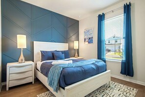 A bedroom with a bed, two bedside tables, a nightstand, a window with curtains, and a wall with a geometric design. - Resort Access/7br Family-villa/close2parks! (Clermont)