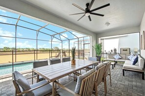 A spacious patio with a pool, outdoor seating, and a ceiling fan. - Resort Access/7br Family-villa/close2parks! (Clermont)