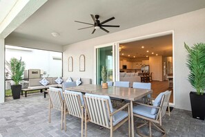 An outdoor patio area with a dining table, chairs, and a ceiling fan. - Resort Access/7br Family-villa/close2parks! (Clermont)