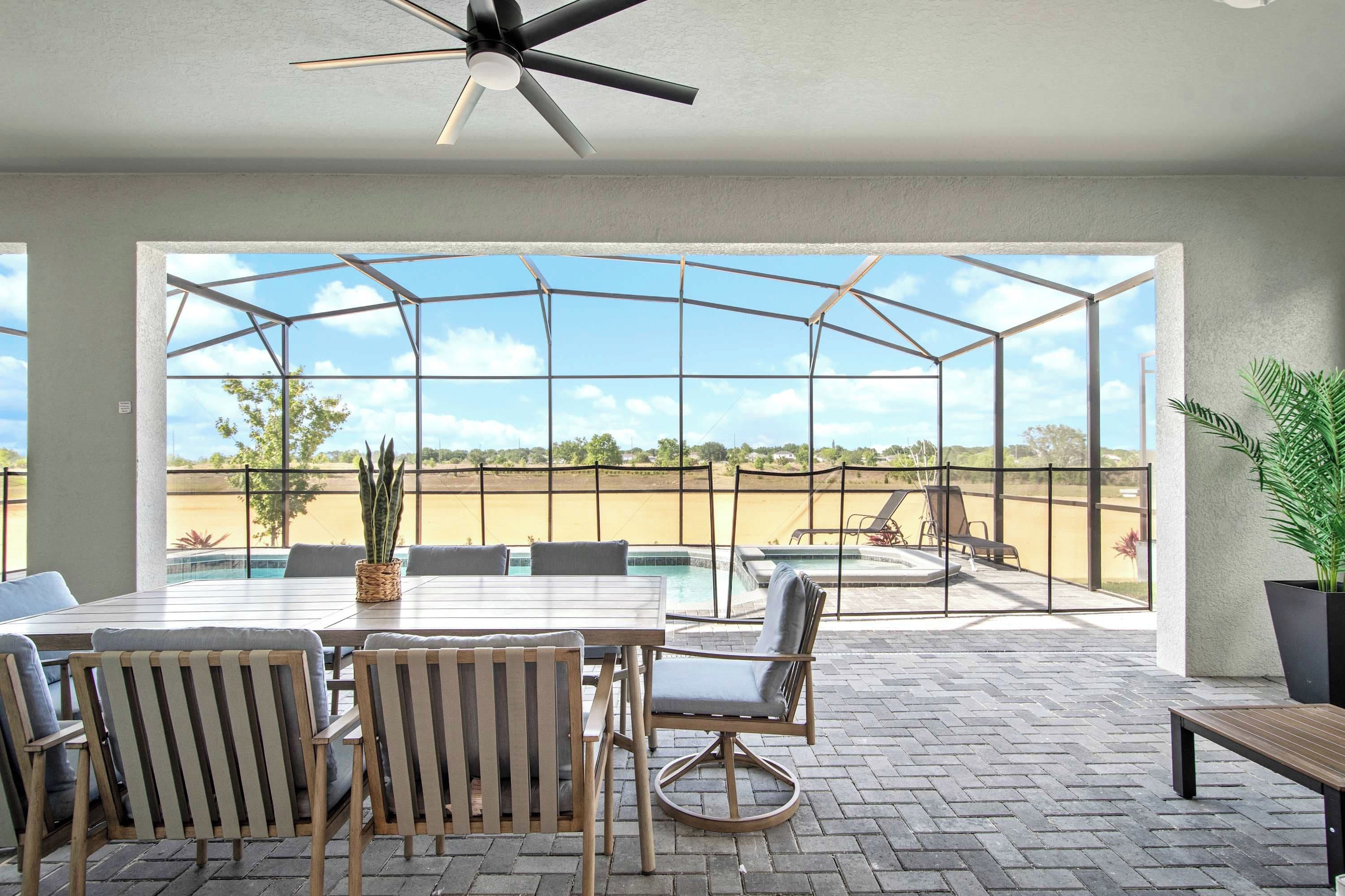 A covered patio area with a pool, outdoor furniture, and a view of the landscape.
