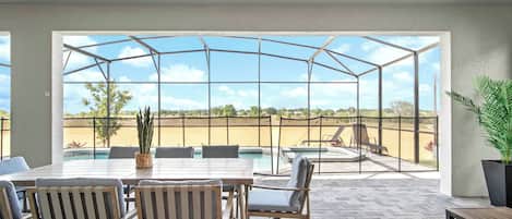 Un patio techado con piscina, muebles de exterior y vistas del paisaje.