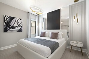 A modern bedroom with a large bed, a bedside table, a wall art piece, and a window with blinds. - Avatar Gameroom/theater/resort Access/huge 15br! (Kissimmee)