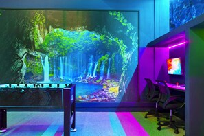 A room with a large wall mural of a waterfall, a foosball table, and gaming chairs. - Avatar Gameroom/theater/resort Access/huge 15br! (Kissimmee)