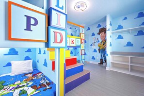 Une chambre d’enfant avec un lit, des cubes d’alphabet et une poupée à l’effigie de Woody.