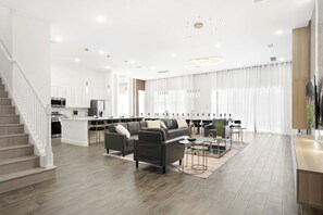 Un vaste espace de vie comprenant un ensemble de canapés, une table basse et un téléviseur posé sur un meuble en bois.