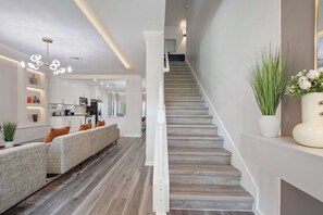 Un intérieur moderne comprenant un escalier, un ensemble de canapés et un coin cuisine.