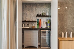 Eine kleine Küche mit Marmorfliesenspiegel, einem integrierten Kühlschrank und einem Holzkorpus.
