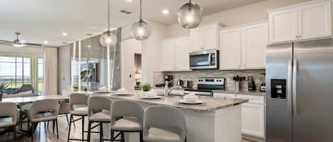 A modern kitchen with white cabinets, stainless steel appliances, and a bar area with stools.