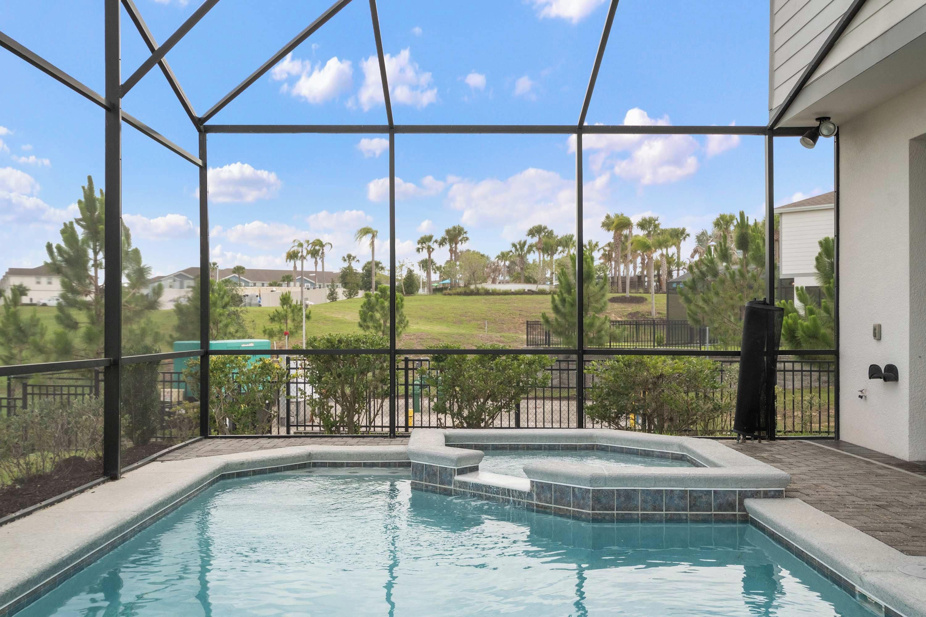 A swimming pool with a view of a residential area, surrounded by a metal fence.