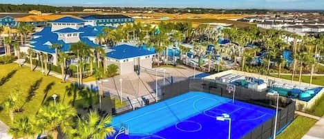 Zona residencial con una gran cancha de baloncesto azul rodeada de palmeras y viviendas.