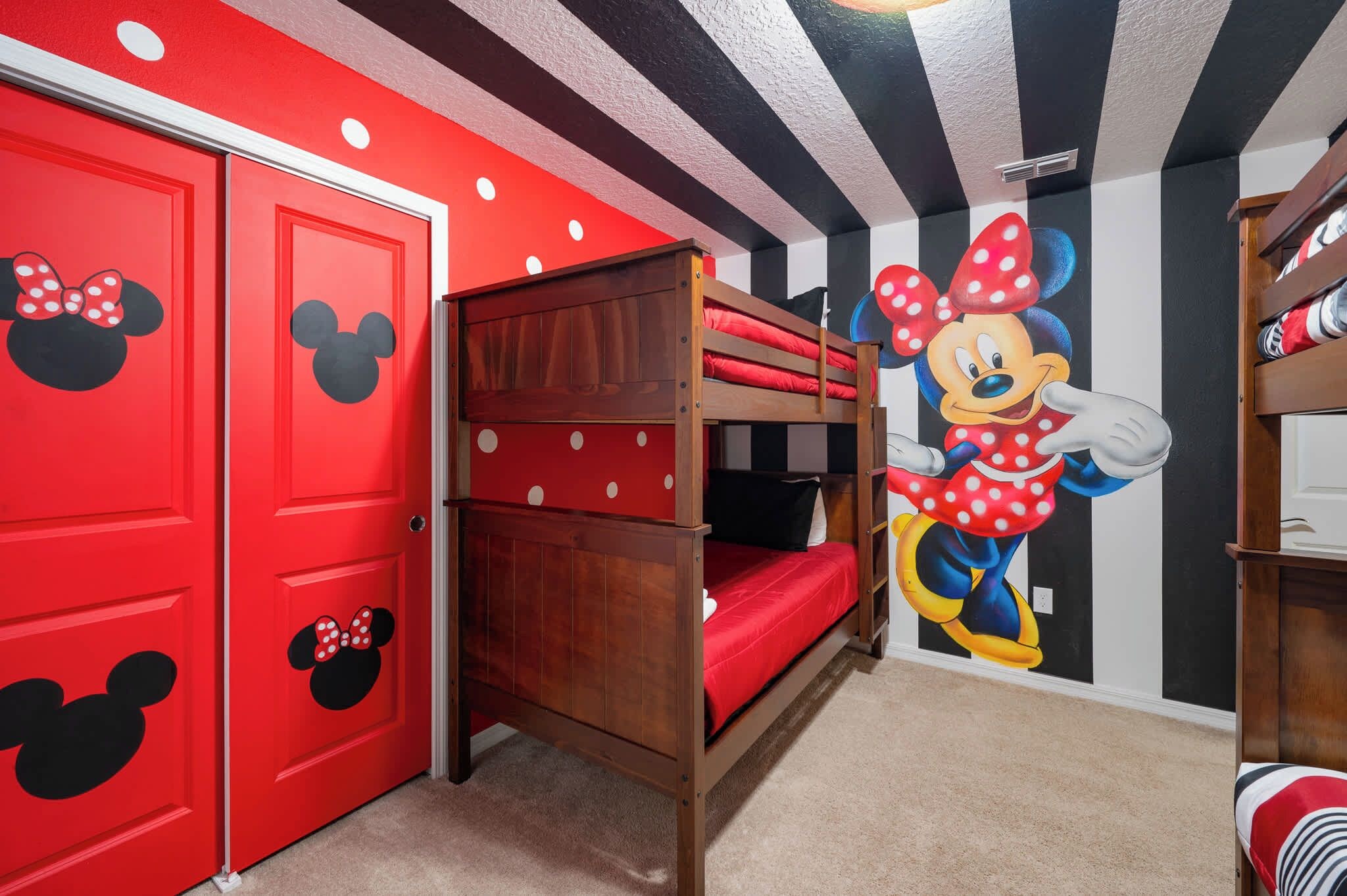 Una habitación con puertas rojas, un mural de Minnie Mouse y una cama litera.