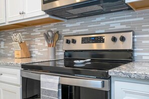 A kitchen with a stainless steel range hood, a digital oven control panel, and a granite countertop. - Windsor Island Stay w Pool, Resort Access, Parks (Davenport)
