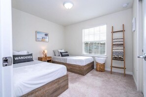 A bedroom with two beds, a window with blinds, a bedside table with a lamp, a woven basket, and a wooden ladder. - Windsor Island Stay w Pool, Resort Access, Parks (Davenport)
