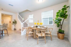 A dining area with a round table and chairs, a staircase, and a potted plant. - Windsor Island Stay w Pool, Resort Access, Parks (Davenport)