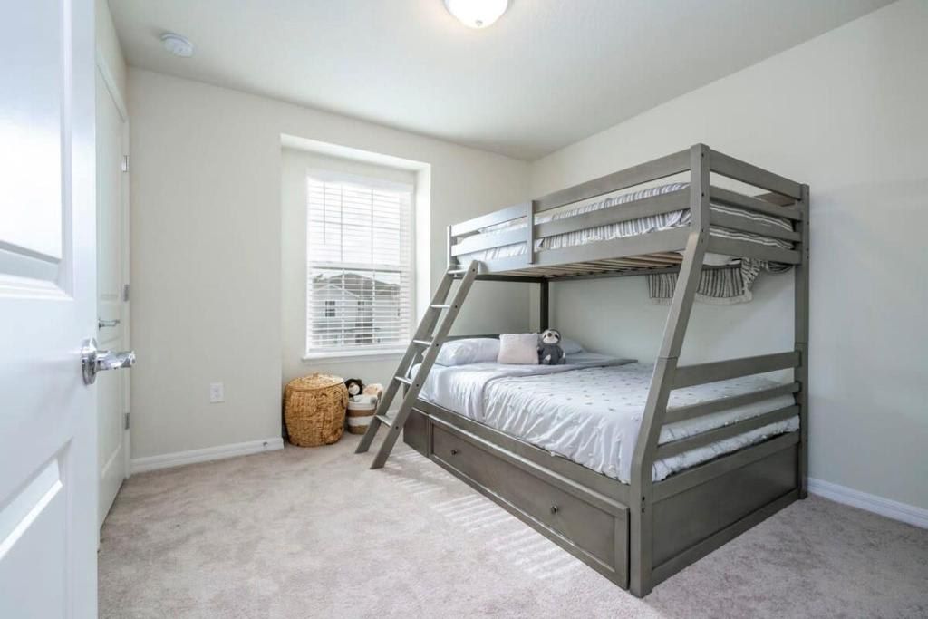 A bunk bed in a room with a window, carpeted floor, and a door.