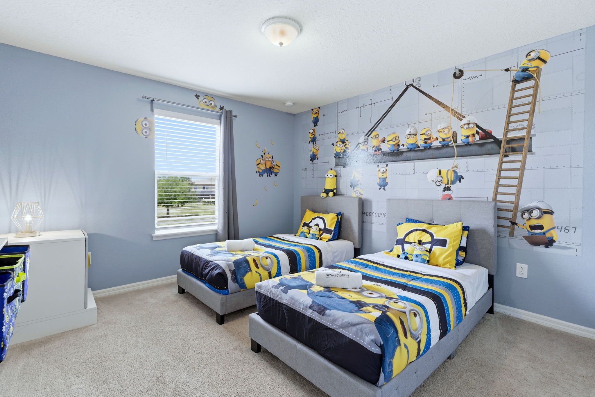 A bedroom with two beds, a window, a desk, and a ladder.