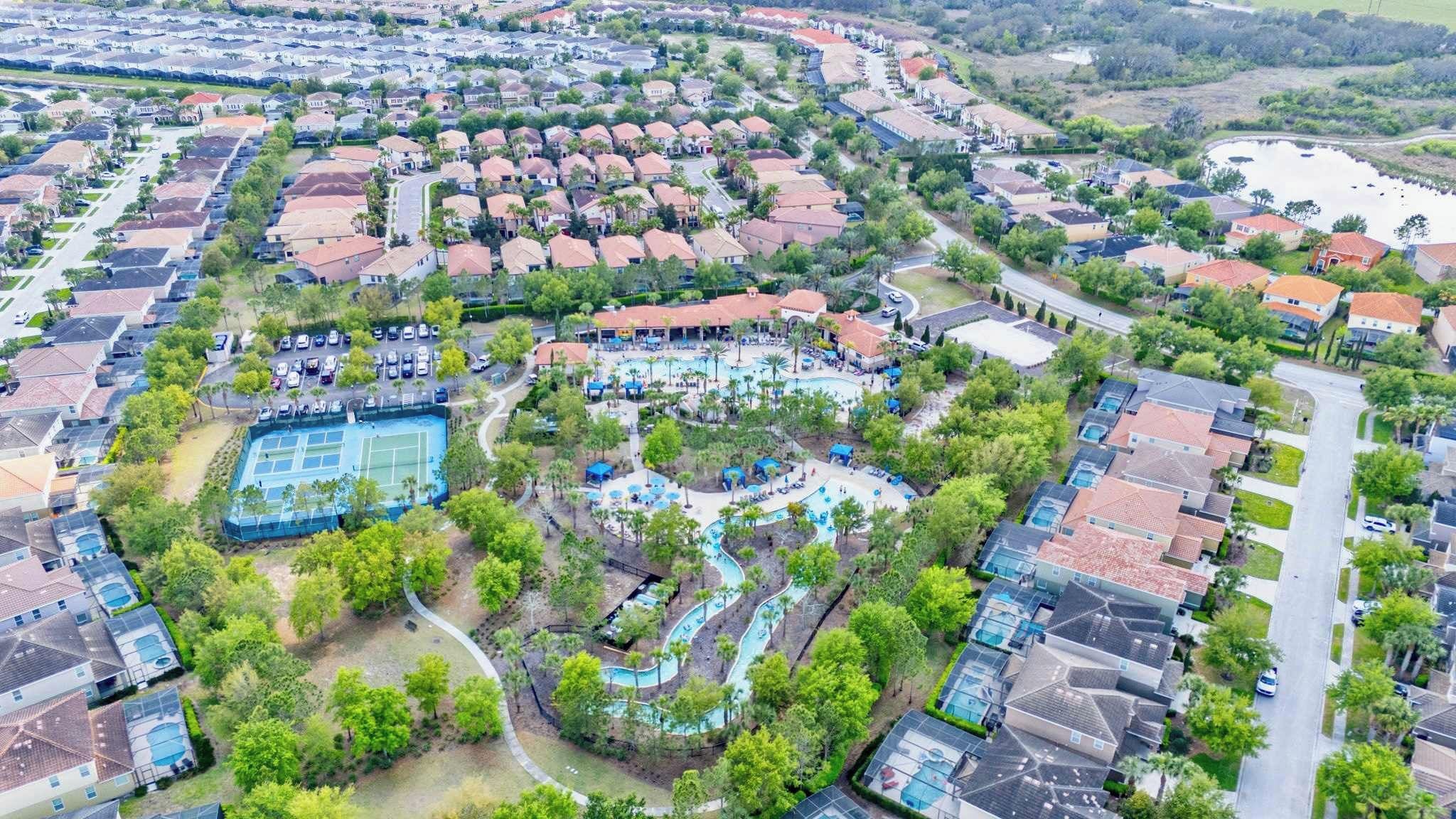 A residential area with a large swimming pool, tennis courts, and a winding water feature.