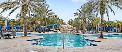 A pool area with palm trees, lounge chairs, and a central water feature.