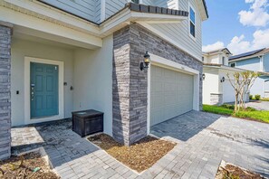 A residential building with a blue door, a garage, and a stone accent wall. - Enchanted Palms Villa 7BR w Private Pool (Davenport)