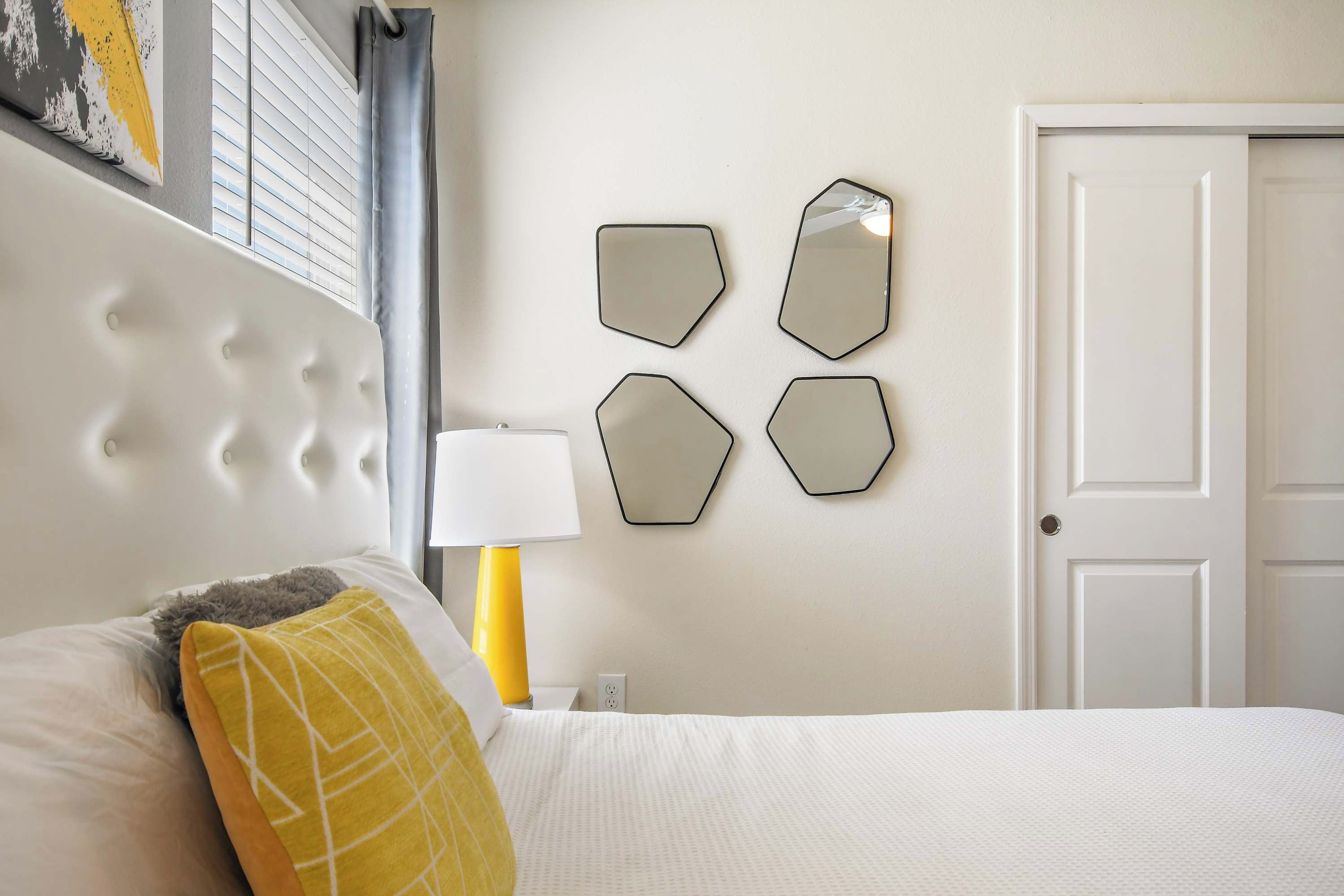 A hotel room with a bed, a nightstand, a lamp, and a door.