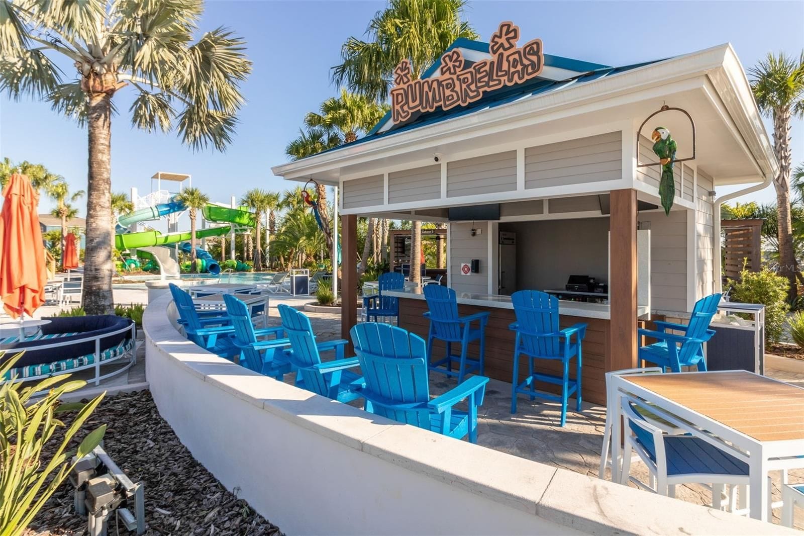 A poolside area with blue chairs, a bar, and a sign that reads 'CUMBRELLAS'.