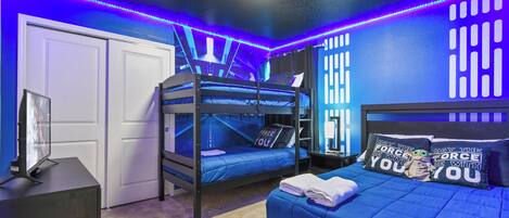 A room with bunk beds, a desk with a computer, and Star Wars themed pillows.