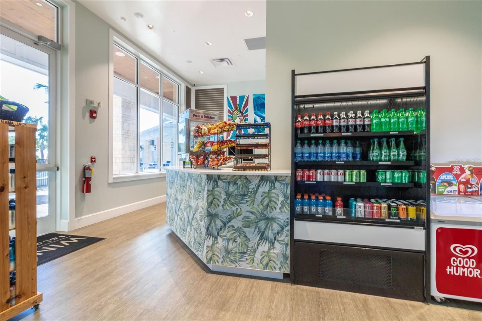 A reception area with a counter, a tropical-themed wallpaper, and a beverage dispenser.