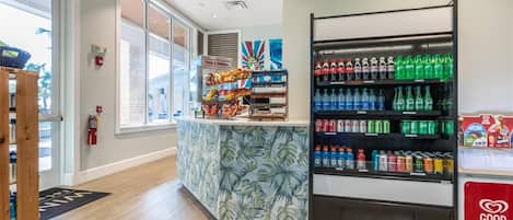 A reception area with a counter, a tropical-themed wallpaper, and a beverage dispenser.