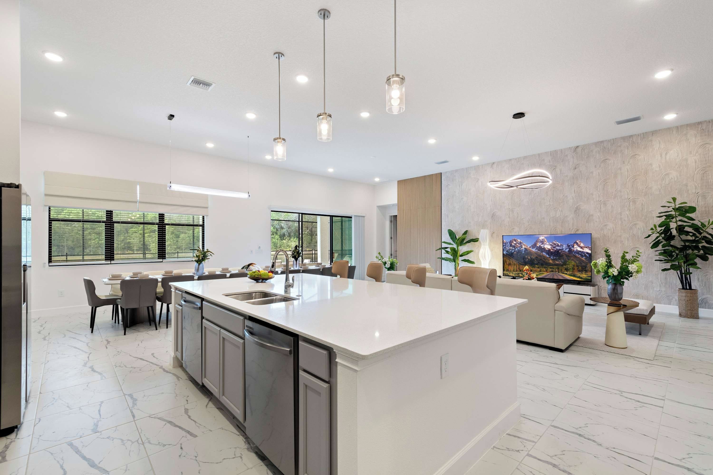 A spacious kitchen with a large island, modern pendant lights, and a dining area with chairs and a table.