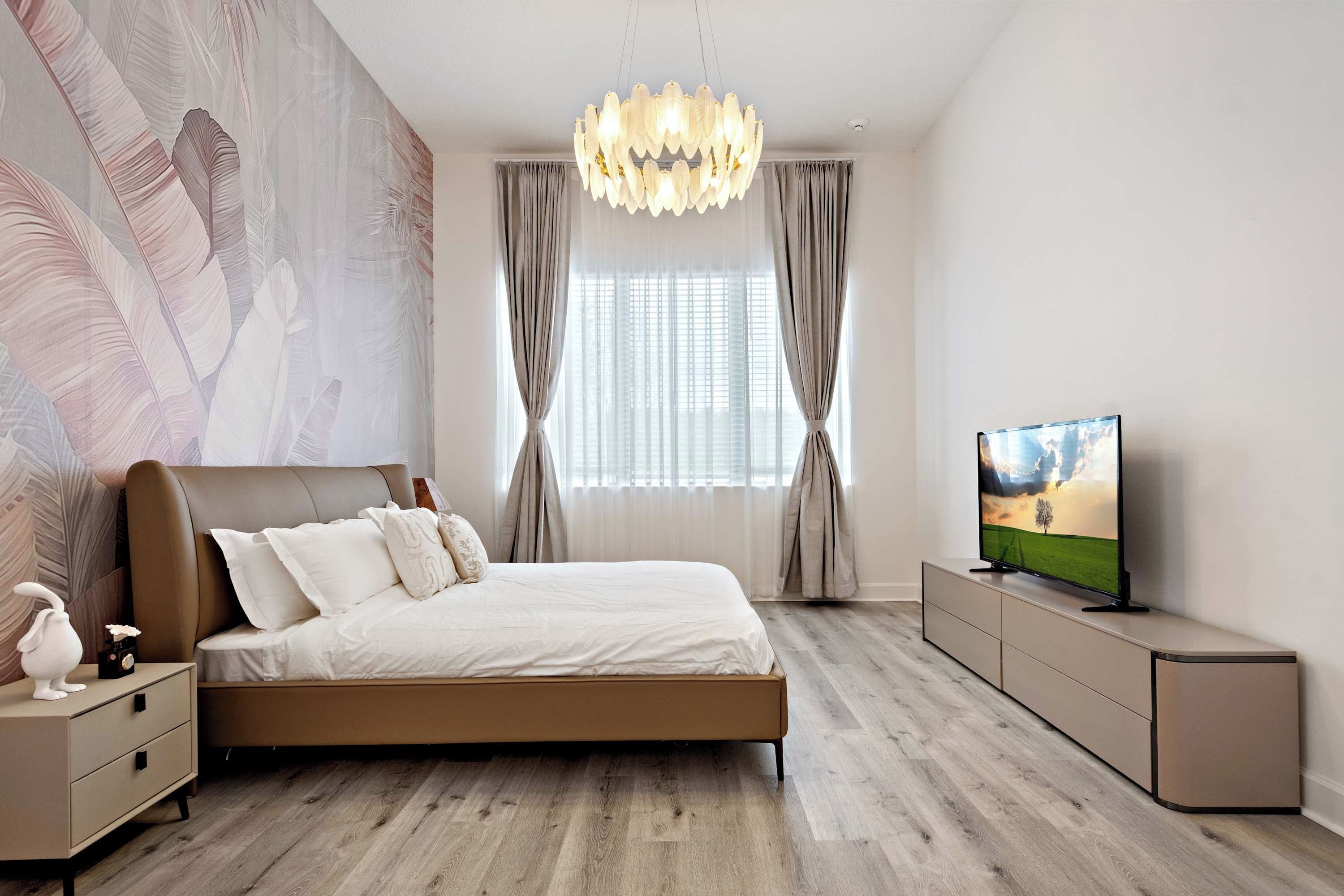 Un dormitorio moderno con una cama grande, un televisor en un mueble bajo y una pared decorativa.