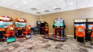 Un salón de juegos recreativos con diversas máquinas, incluyendo juegos de carreras y de lucha.