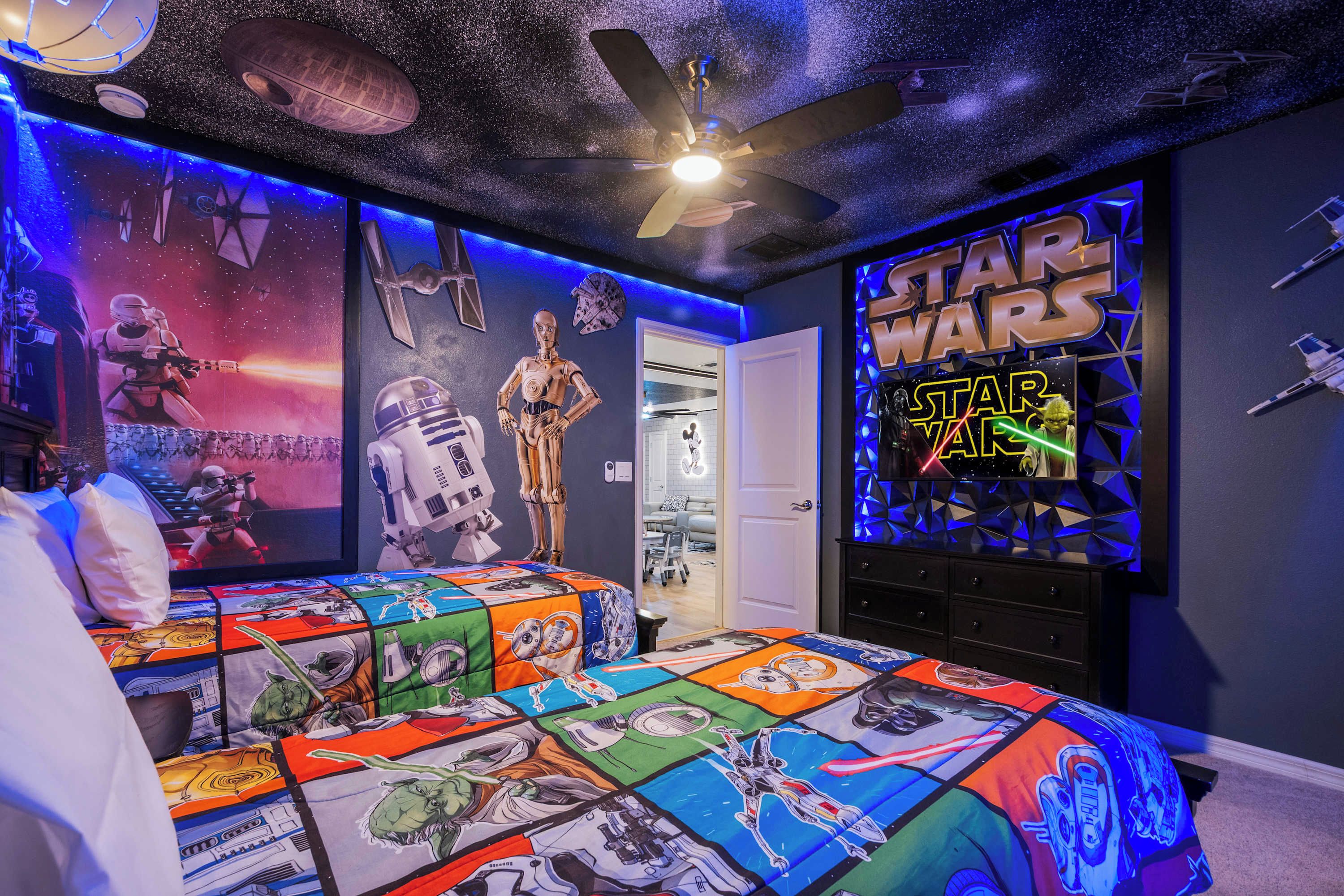 Een slaapkamer in Star Wars-thema, met een bed, posters en een plafondventilator.