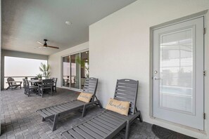 A covered patio with two lounge chairs, a table, and chairs, and a door with a window. - Disney Dream Home Mario, Frozen & Minions (Davenport)